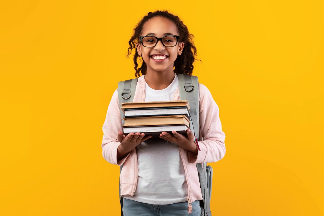 Une étudiante tient une pile de livres